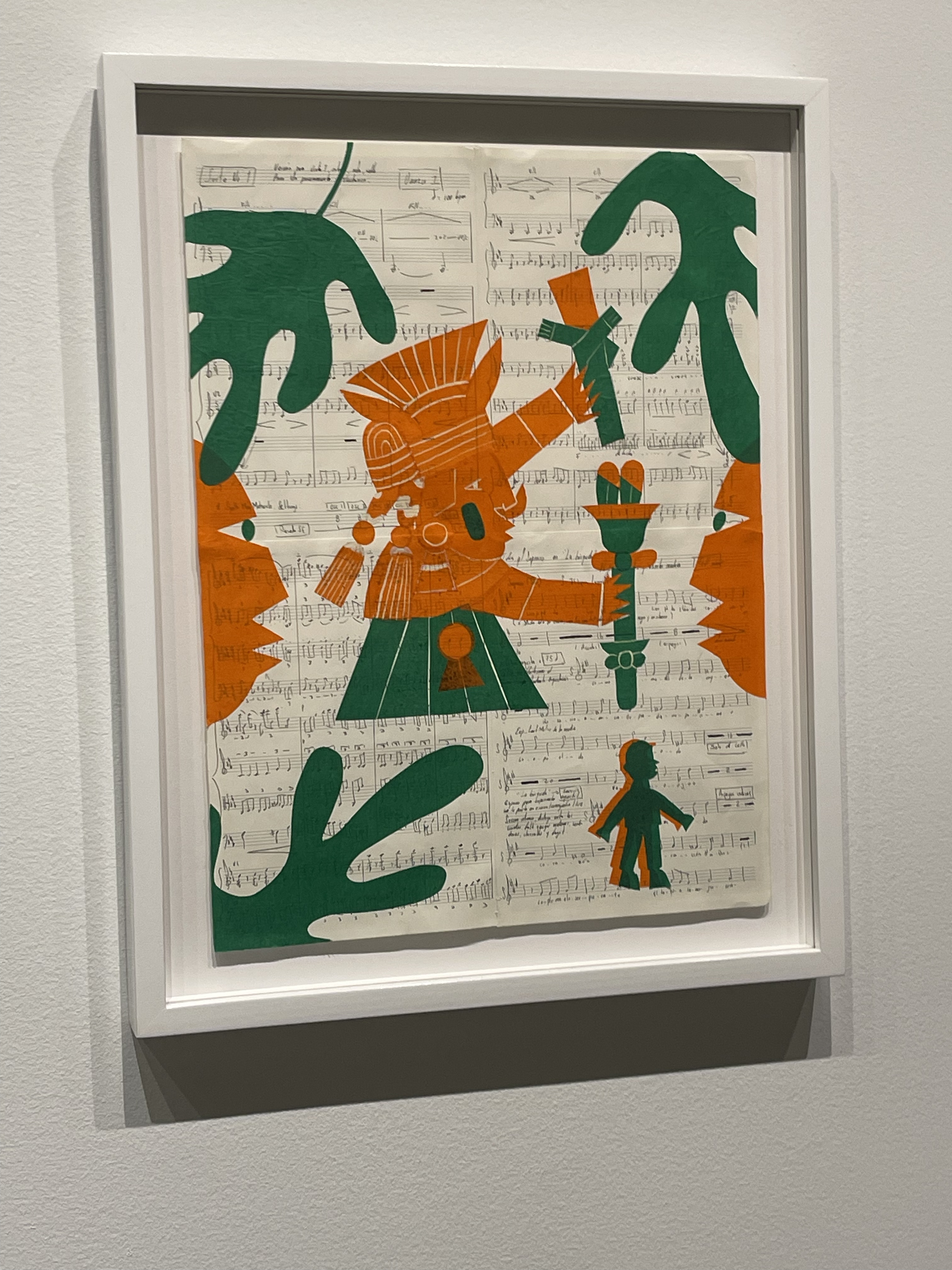 Aztec-style orange and green figure printed over handwritten Western sheet music